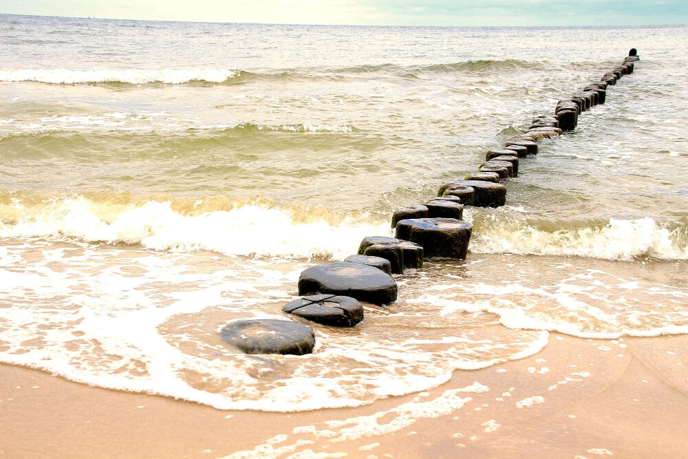 Houten golfbrekers die vanaf het strand de zee in lopen