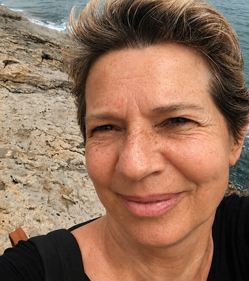 Bernadette van den Oudenrijn, glimlachend aan een rotsachtige kust